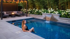 A luxurious modern plunge pool integrated into a beautifully landscaped backyard patio with comfortable lounge seating.