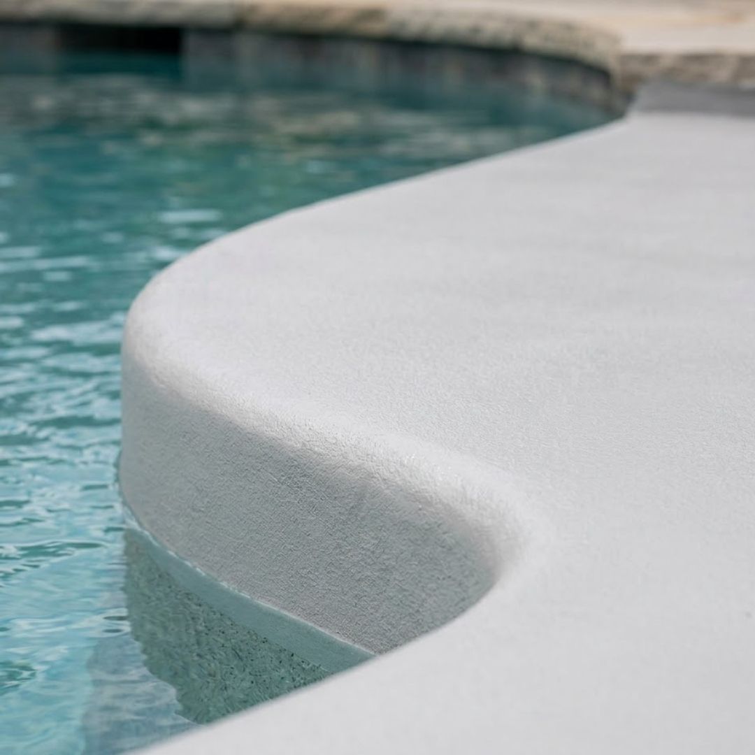 A close-up view demonstrates the flawless, light-grey polyurea coating on a smooth swimming pool edge as clear water laps against the durable, clean surface.